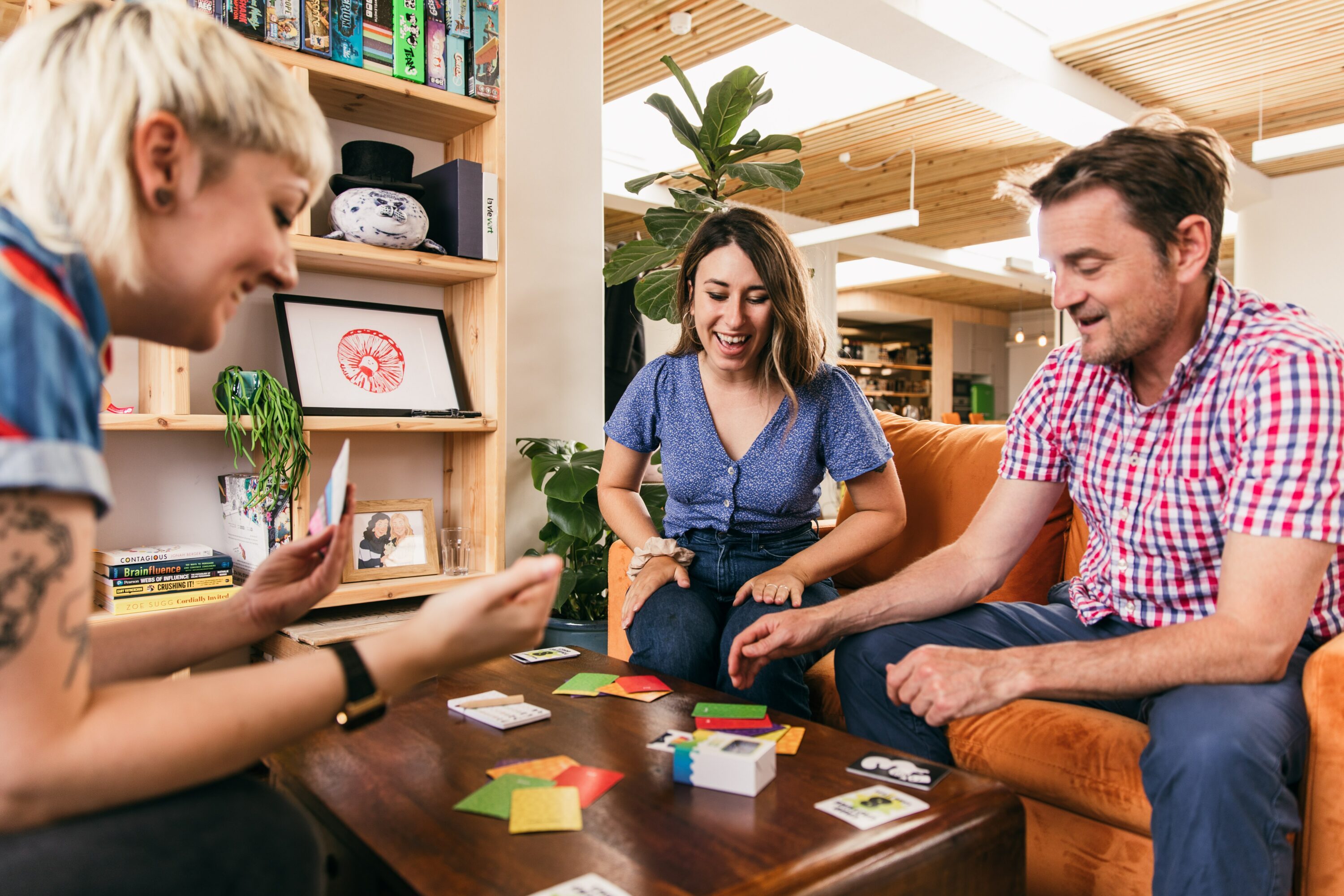 Three adults playing a board game together on a coffee table.