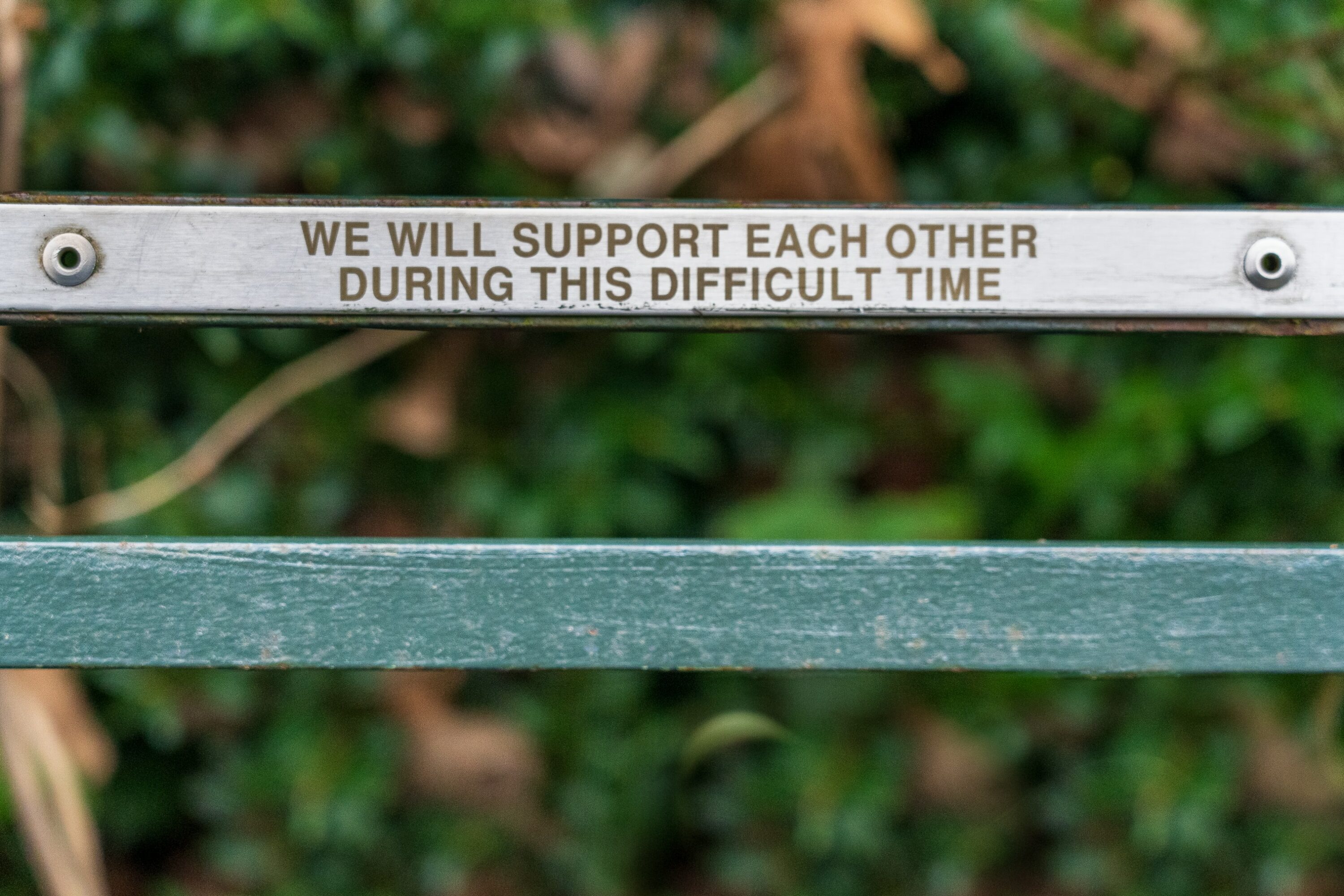 Photo of a wooden sign that says "We will support each other during this difficult time"