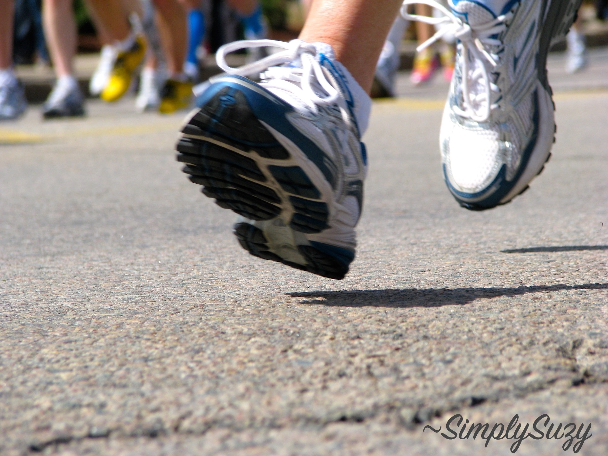 A set of feet running on the pavement during a race.