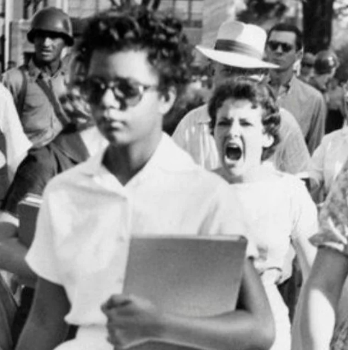 A student of color walking with a white student standing behind, yelling with an angry face.