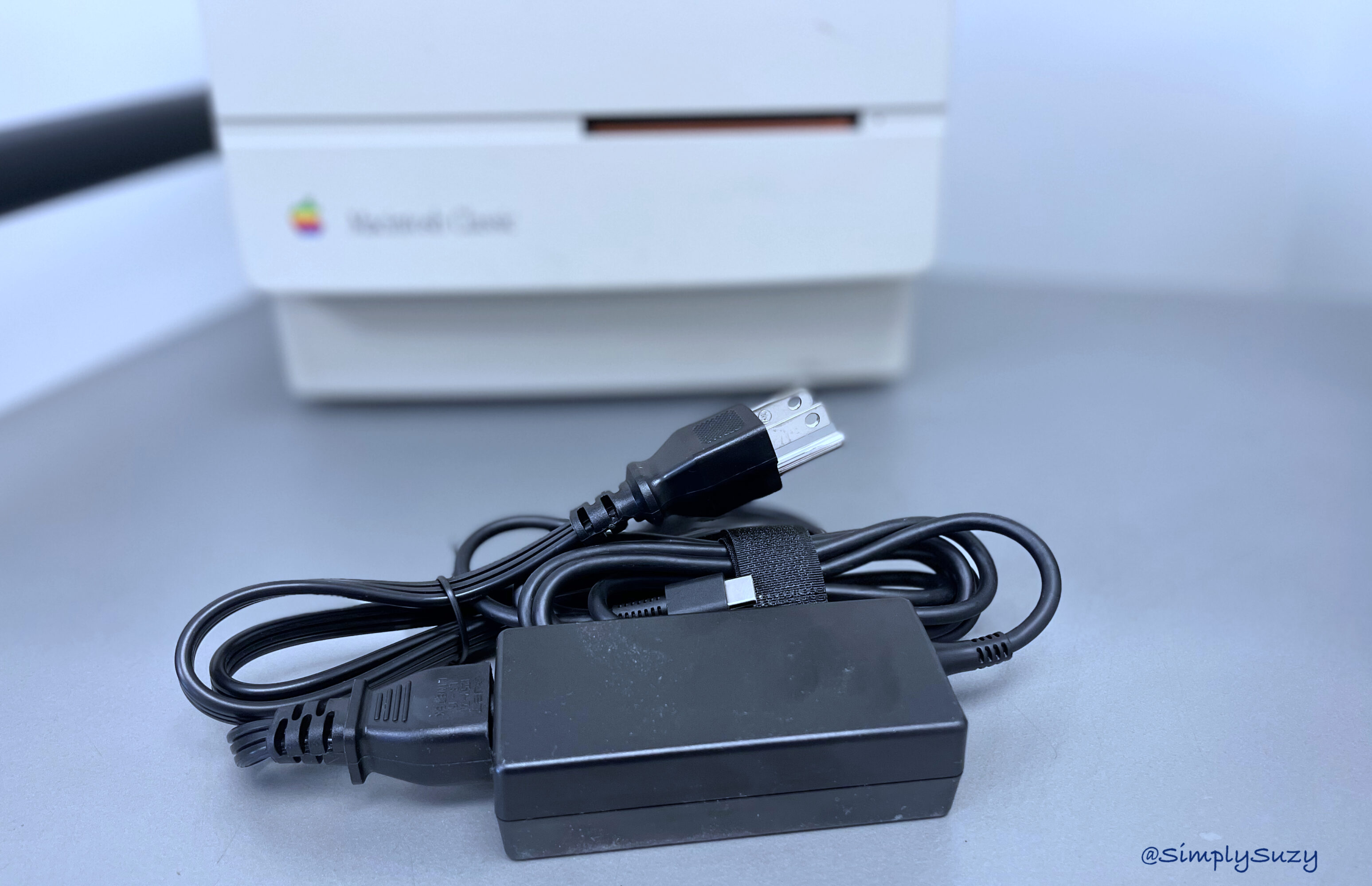A Macintosh Classic in the background with a powercord wrapped up in the foreground.