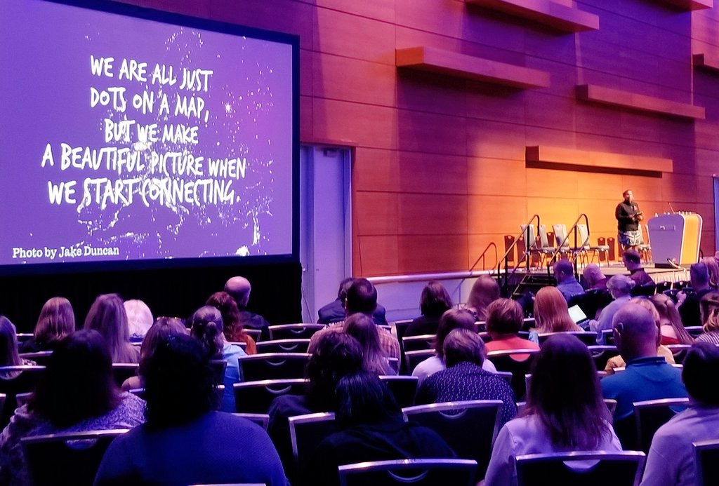 auditorium presentation of a presenter, an audience and a big screen for a presentation.