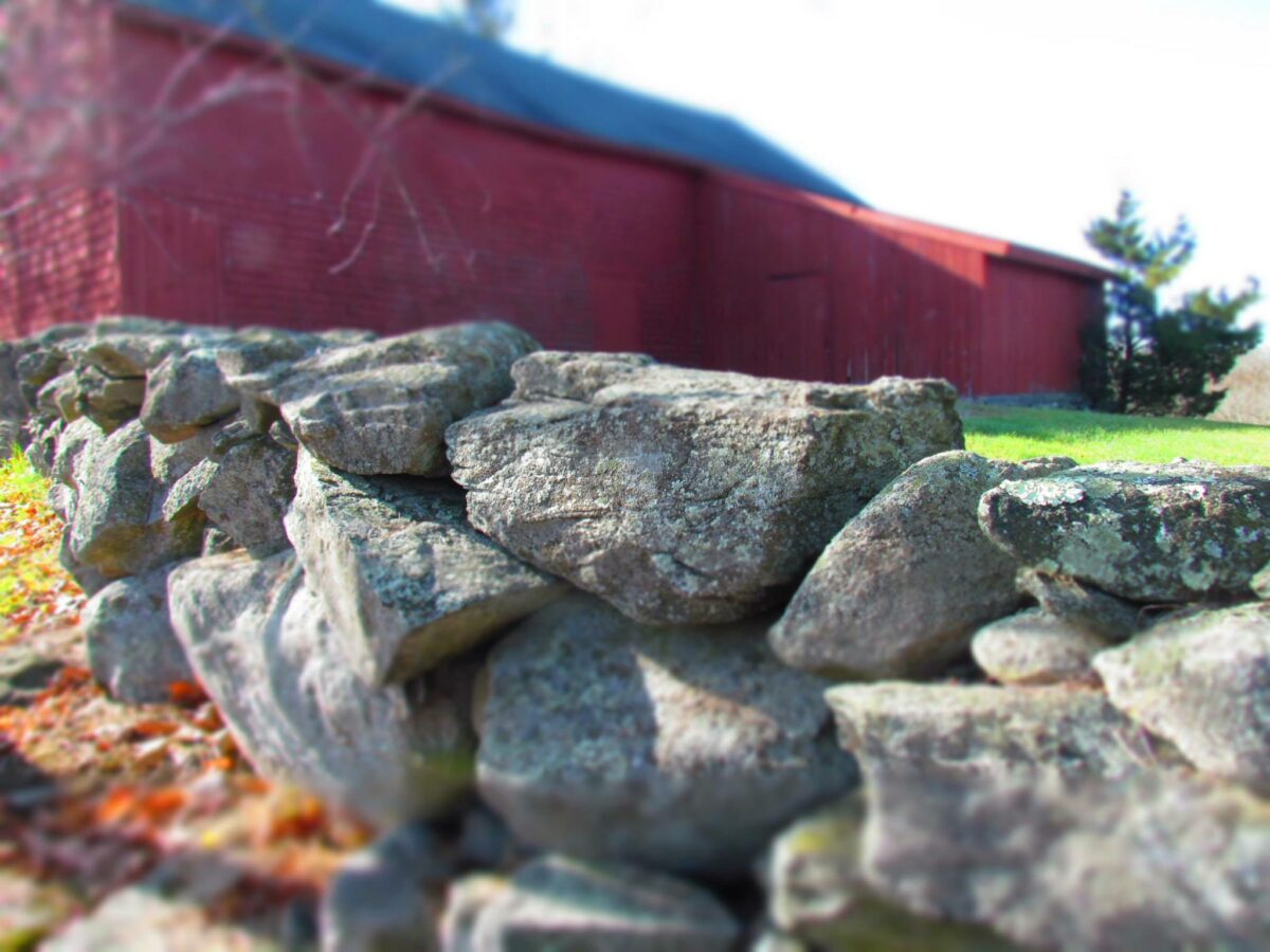 Stone wall beside a red barn in Stonington, CT.