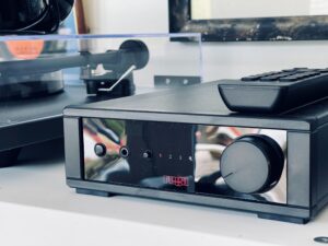 A stereo amplifier, microphone, turntable and remote control sitting on a table.